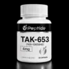 TAK Close-up of a white medicine bottle with a ribbed cap. The label shows TAK-653 (NBI-1065846) and 30 capsules on a black background.